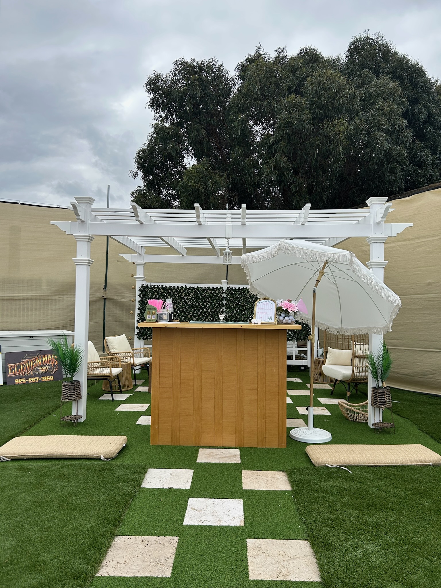 Pour It Out mobile bar set up under a white pergola with garden seating and a checkered floor at a private venue