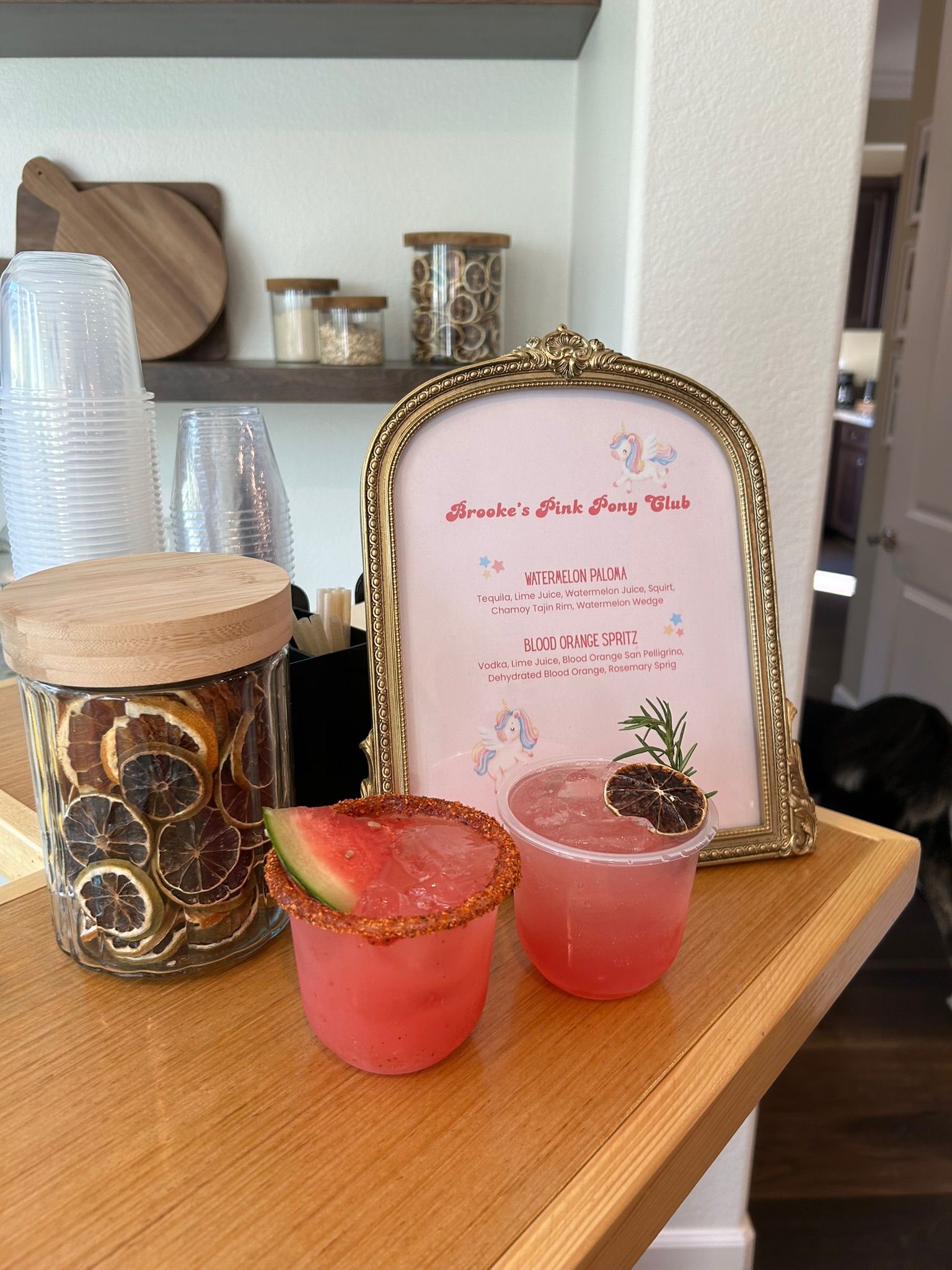Brooke's Pink Pony Club themed watermelon paloma and blood orange spritz beside a unicorn custom cocktail menu